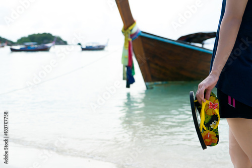 Beach travel - girl hold slippers while walking on the white sand beach, vacation and relax