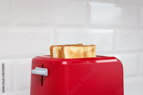 Red toaster with bread slices on white background