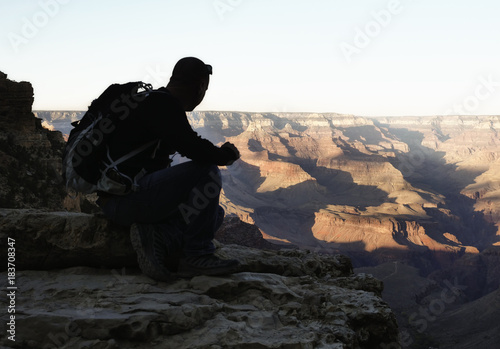 silhouette of a man sitting on the south rim of the Grand Canyon