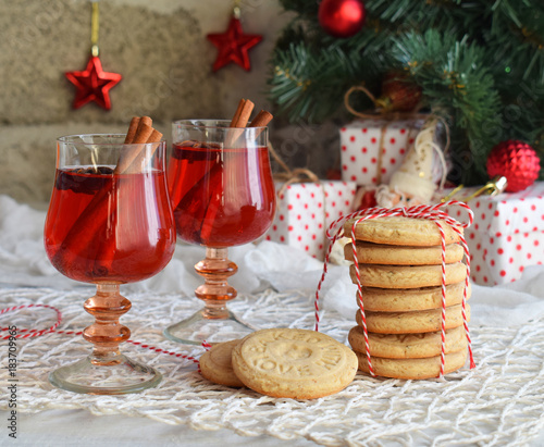 Christmas and new year holiday celebration concept background. Glass of mulled wine with spices, homemade cookie, xmas tree decoration on wooden table
