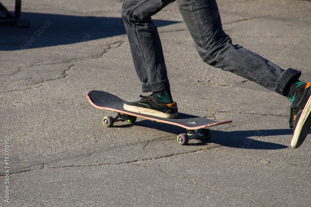 Skateboarder legs riding skateboard at skatepark Skateboarder legs riding skateboard at skatepark