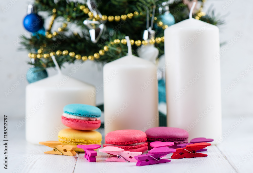 Sweet and colorful macaroon cookies against a background of candles and Christmas tree Sweet and colorful macaroon cookies against a background of candles and Christmas tree