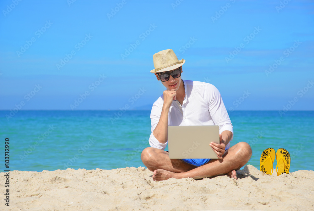 smart man on sitting beach with notebook on line, enjoy and relax in comfortable emotion on the sea beach at sunlight, cleared blue sky in background