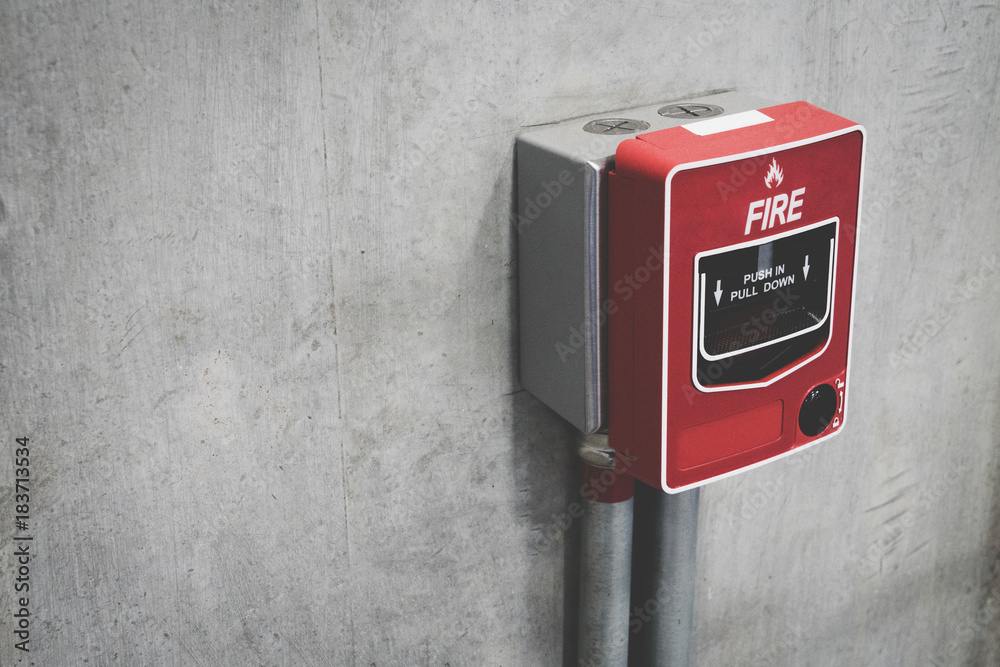 Fire alarm switch on the concrete wall in building for safety with copy space for text. Close-up of fire alarm machine.