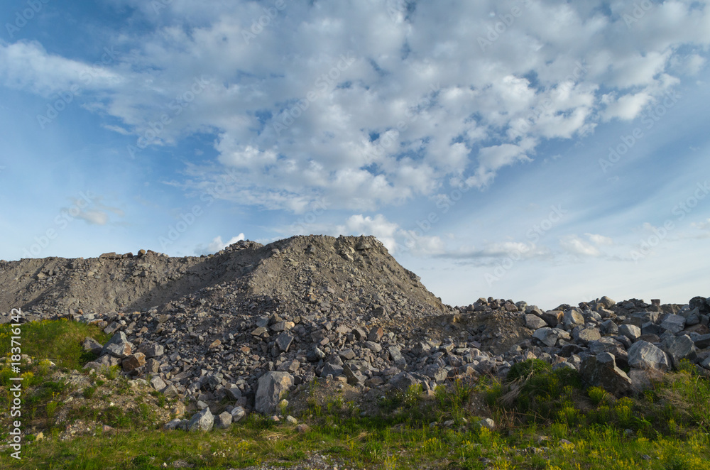 Quarry, piles of rocks and gravel,the sky and clouds.