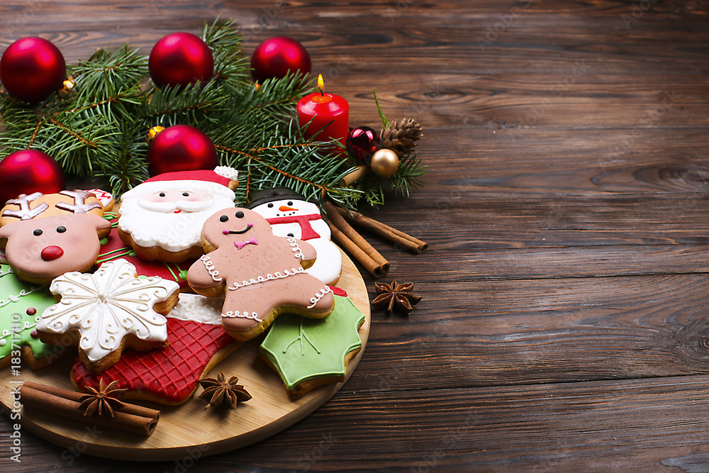 Various types of Christmas gingerbread cookies with fir tree branches, cinnamon sticks, anise star, candle and decoration top view on wooden table with copy space. Christmas holiday sweets food