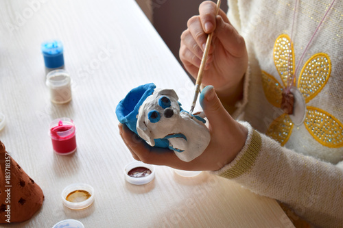 Making toys, paints a pottery clay dog figure with gouache. Indoors creative leisure for children. Supporting creativity, learning by doing, DIY project, hand craft. Master class of art.