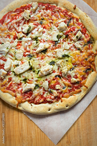 Pizza with tomato sauce, green pesto, cheese and chicken 