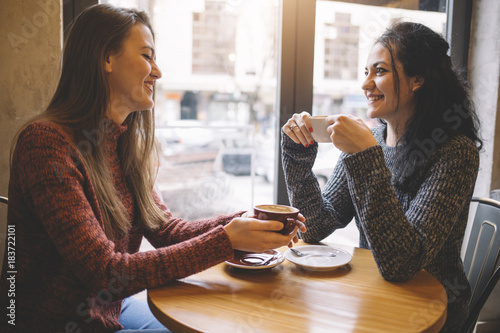 The girls drink coffee in the cafe.