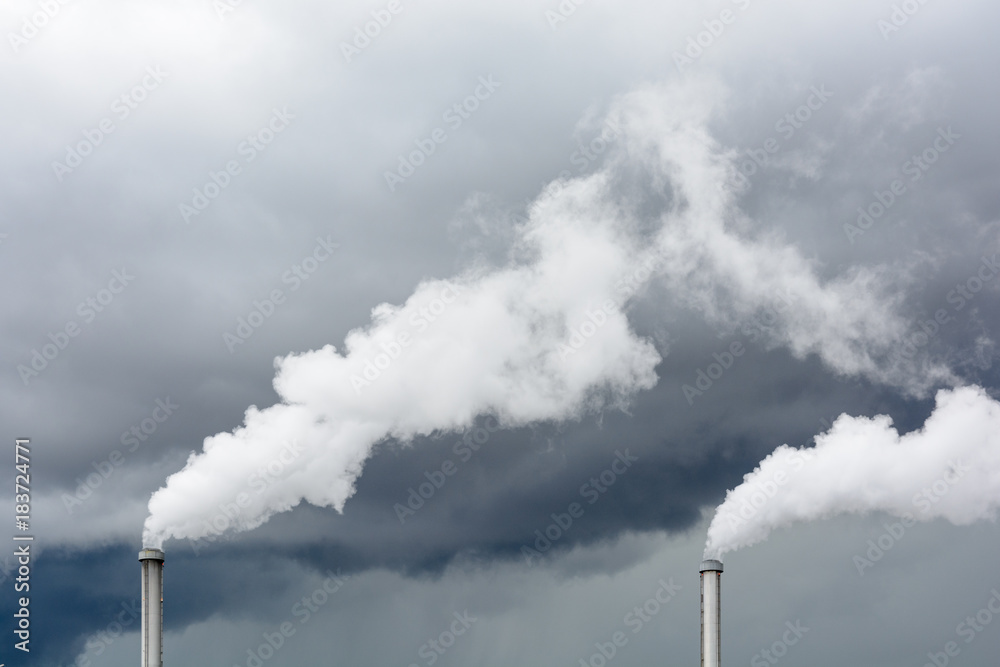 Industrial smoke emission from factory chimney under a stormy sky. Industrial smoke emission from factory chimney under a stormy sky.