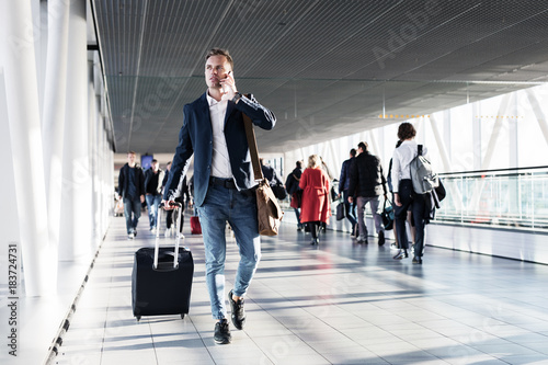 Busy man speaking on phone and walking in airport photo