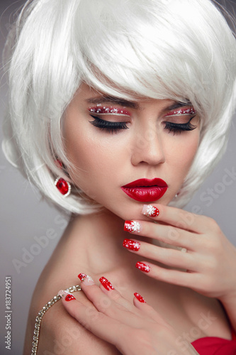 Christmas makeup. Red lips Make-up. Beautiful blond closeup portrait. Manicured nails. Jewelry. White Short bob hairstyle. Sensual blonde woman with xmas eye shadow. Vogue style.