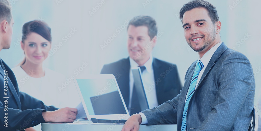 Portrait of mature business man smiling during meeting with colleagues in background Portrait of mature business man smiling during meeting with colleagues in background