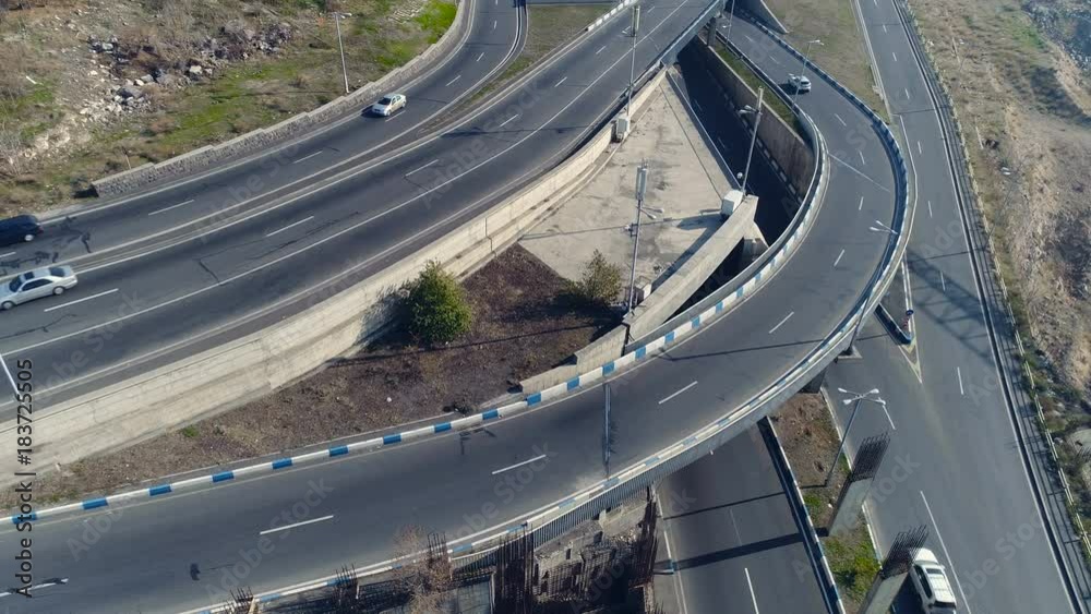 Aerovideo: unmanned aircraft flying over free interstate expressway with machines at summer day. The modern architecture of curvy autoban, many different winding turn. Casual lifestyle in megapolis Aerovideo: unmanned aircraft flying over free interstate expressway with machines at summer day. The modern architecture of curvy autoban, many different winding turn. Casual lifestyle in megapolis