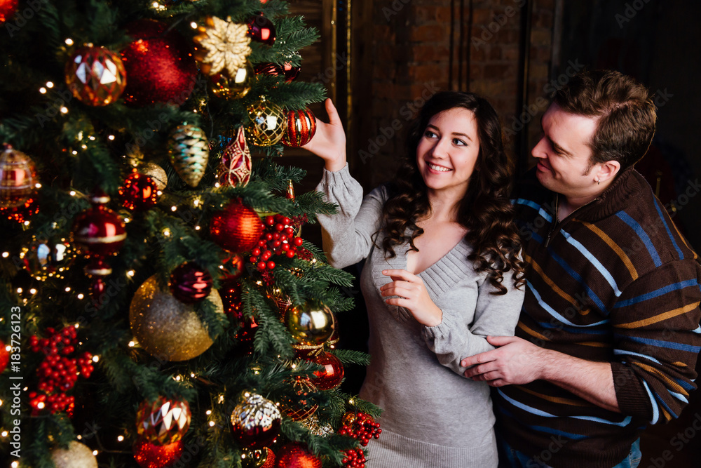 Young couple in love decorates a Christmas tree at home Young couple in love decorates a Christmas tree at home
