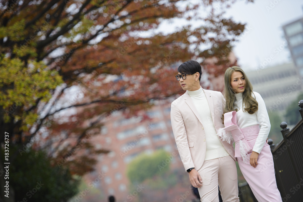 Young japanese couple in love stand together under autumn trees Young japanese couple in love stand together under autumn trees