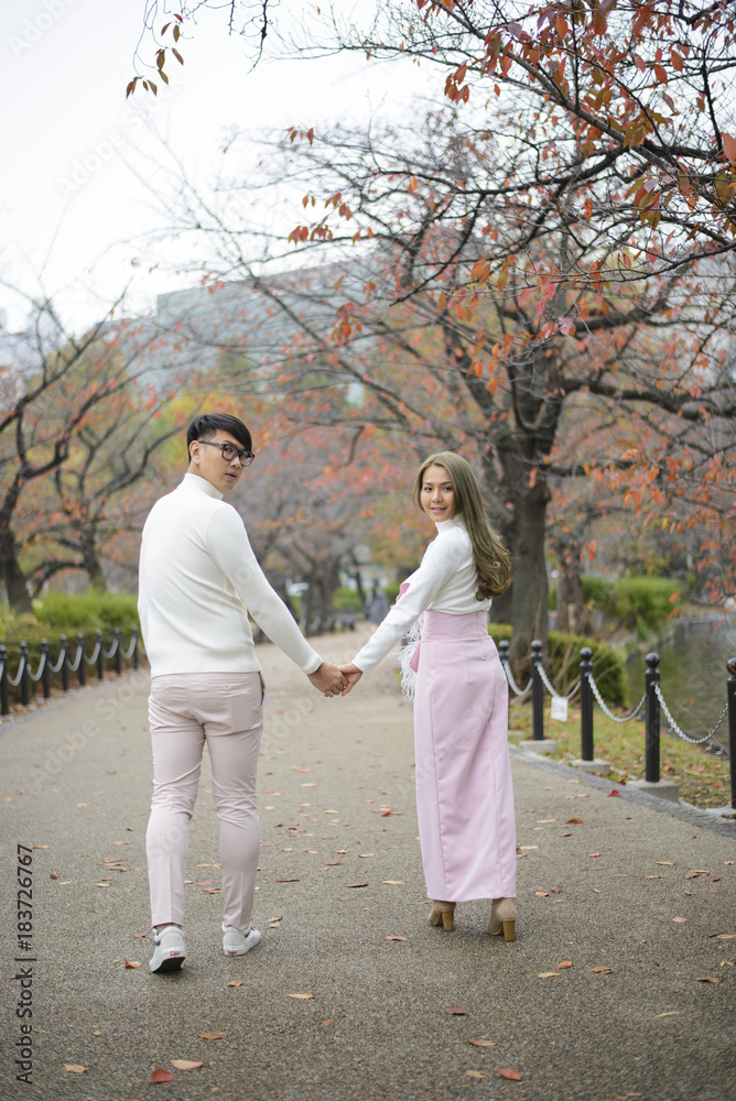Young japanese couple walking together in autumn park