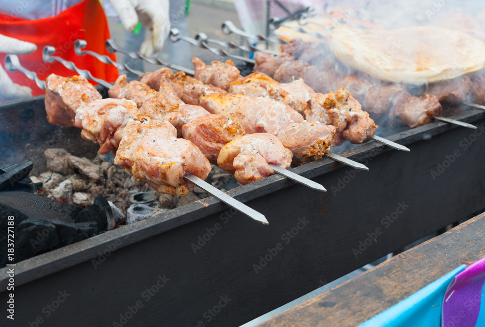 Pieces of meat on skewers are roasted on hot coals.