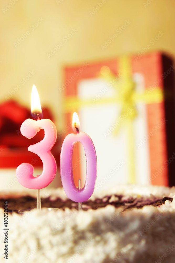 Thirty years. Birthday cake with burning candles and gifts Thirty years. Birthday cake with burning candles and gifts