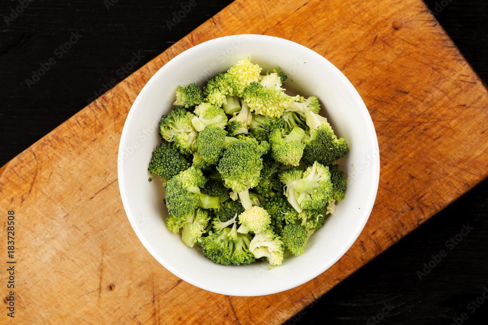 Fresh green broccoli in a white ceramic dish on a wooden board top view Fresh green broccoli in a white ceramic dish on a wooden board top view