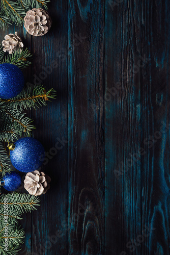 New Year and Christmas decorations Pine tree branches, cones, blue Christmas toys on a wooden background.