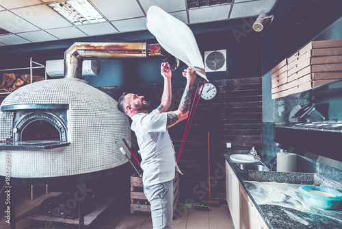 Bearded pizzaiolo chef lunching dough into air