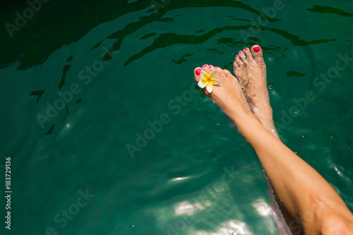 Womans legs with flower in swimming pool