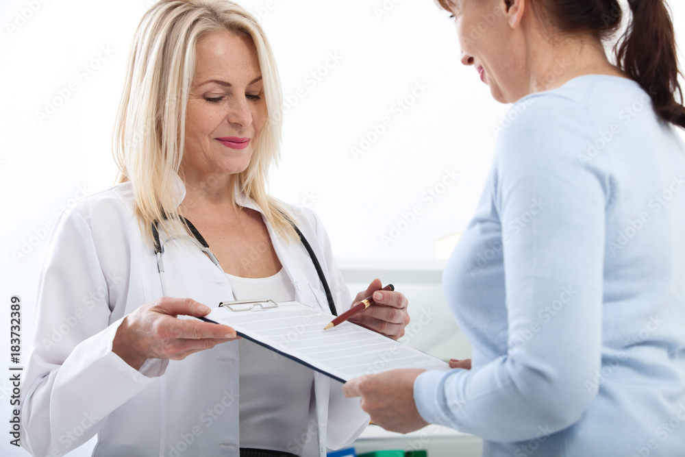 Female doctor holding application form while consulting patient at hospital Female doctor holding application form while consulting patient at hospital
