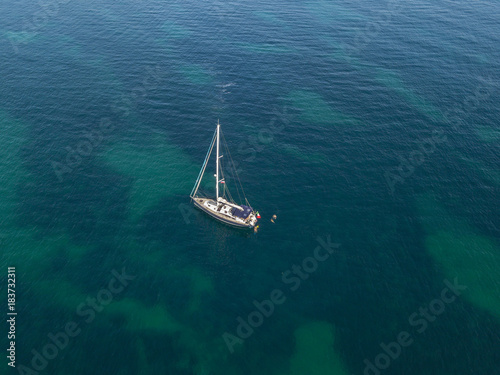 Vista aerea di una barca ormeggiata che galleggia su un mare trasparente. Immersioni relax e vacanze estive. Coste francesi, spiagge e rocce. Corsica. Francia 