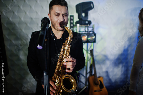 Musicial music live band performing on a stage with different lights. Saxophonist plays.