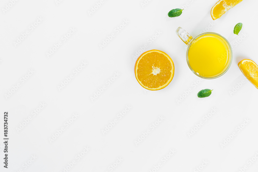 Fototapeta Cut orange, slices, mint leaves, orange juice in a glass top view on a white background, flat lay. The concept of healthy, proper nutrition, ditox.
