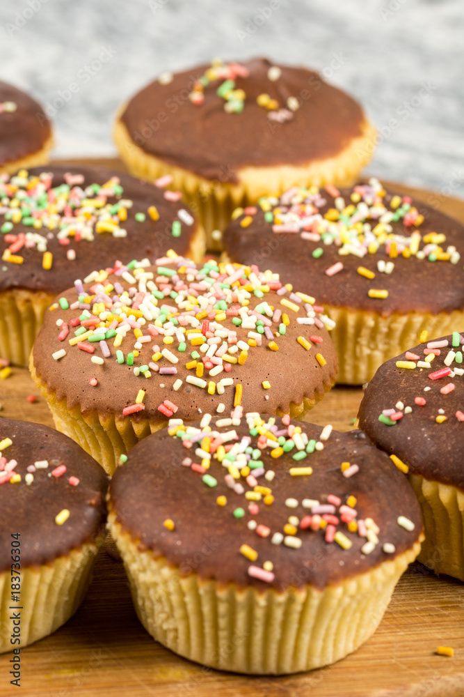 Vanilla cupcakes with chocolate cream and colorful sprinkles