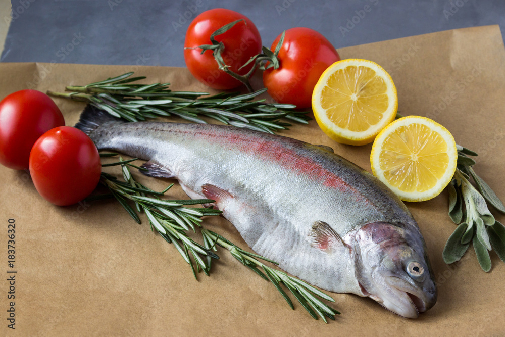 Two raw fish. Fresh trout with lemons, tomatoes and greens. Two raw fish. Fresh trout with lemons, tomatoes and greens.