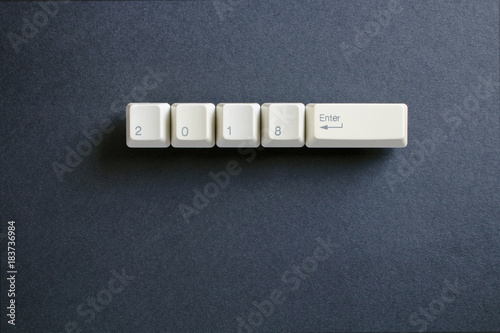 Computer keyboard keys with 2018 enter written using the white buttons on a dark background. Holiday technology concept. New year 2018 card.