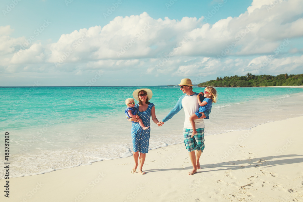 family with two kids walk on tropical beach