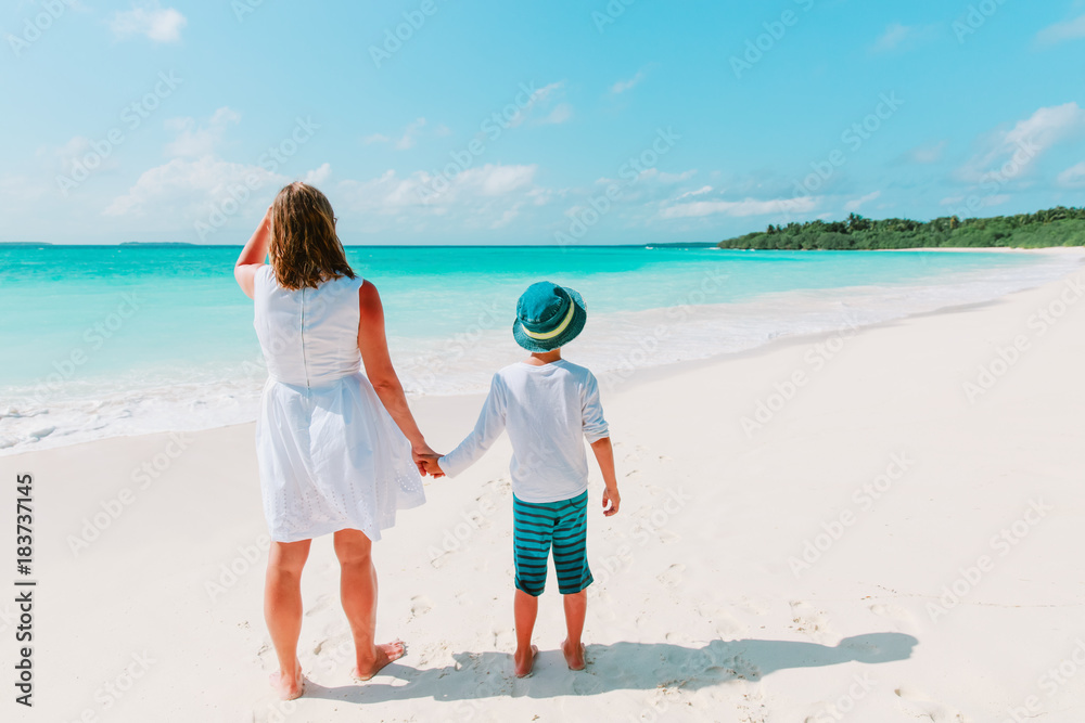 mother and son walk on tropical beach