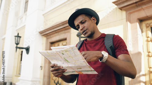 Canvas Print African american tourist man looking into paper city map exploring sightseeings