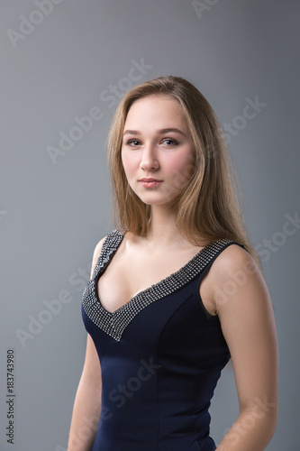young woman with long blonde hair. Studio portrait on a gray background.
