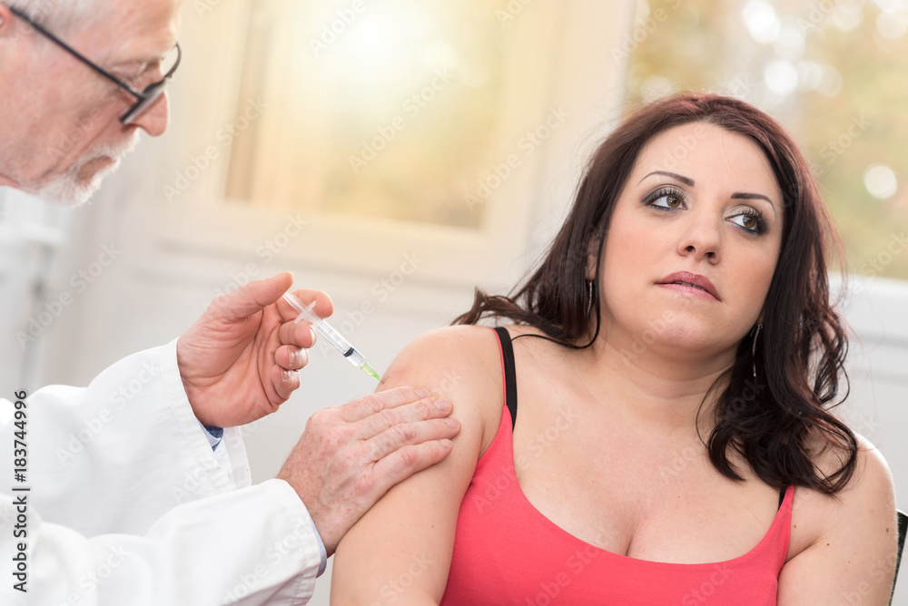 Doctor injecting vaccine to young woman, light effect Doctor injecting vaccine to young woman, light effect
