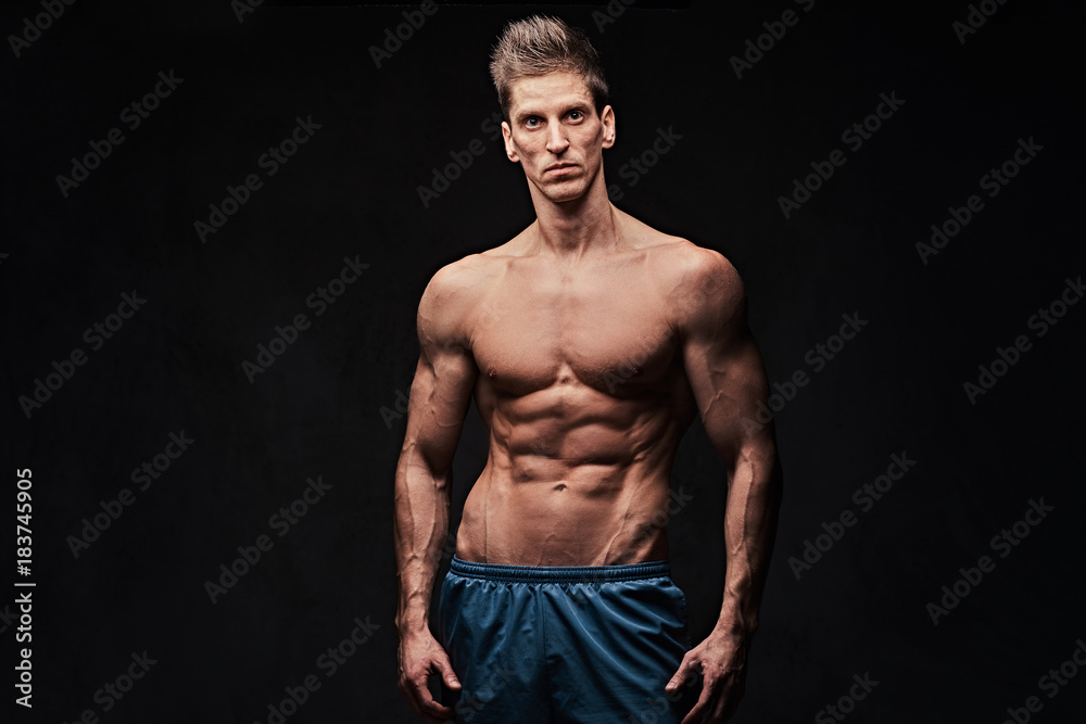 Shirtless muscular male over dark background.