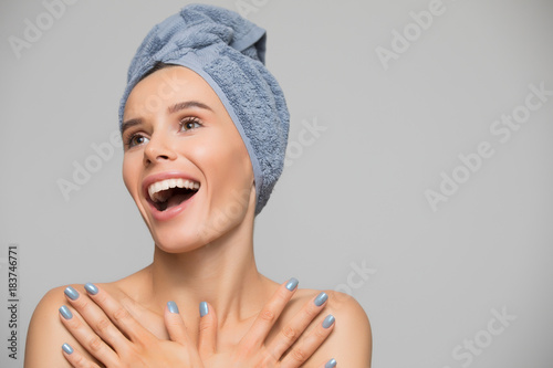 Beautiful spa smiling woman isolated on grey background. She after bath with towel on head.