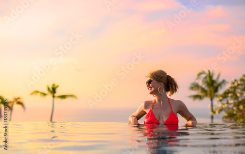 Woman enjoying sunset while relaxing in infinity pool © Kaspars Grinvalds