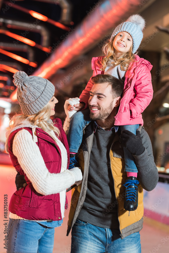 happy young family with adorable little child spending time together on rink