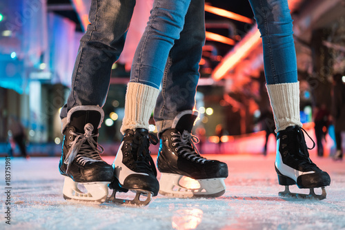 Photo close-up partial view of young couple in skates ice skating on rink