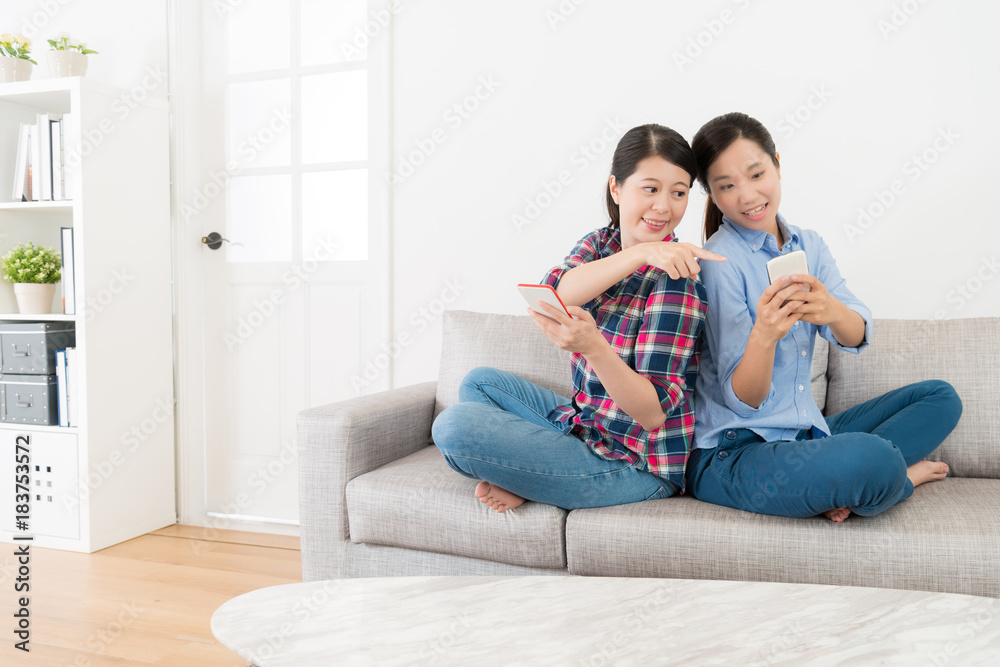 friends back to back sitting on living room sofa