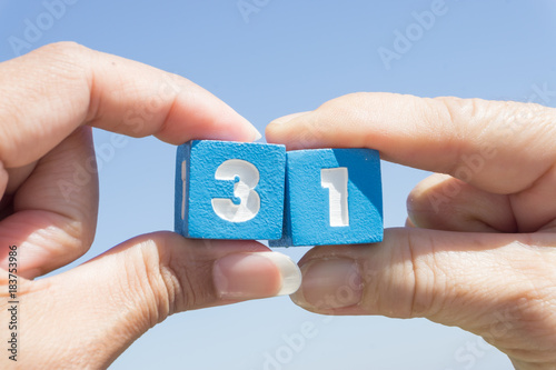 Women's hand Holding Thirty-one number on blue sky background.