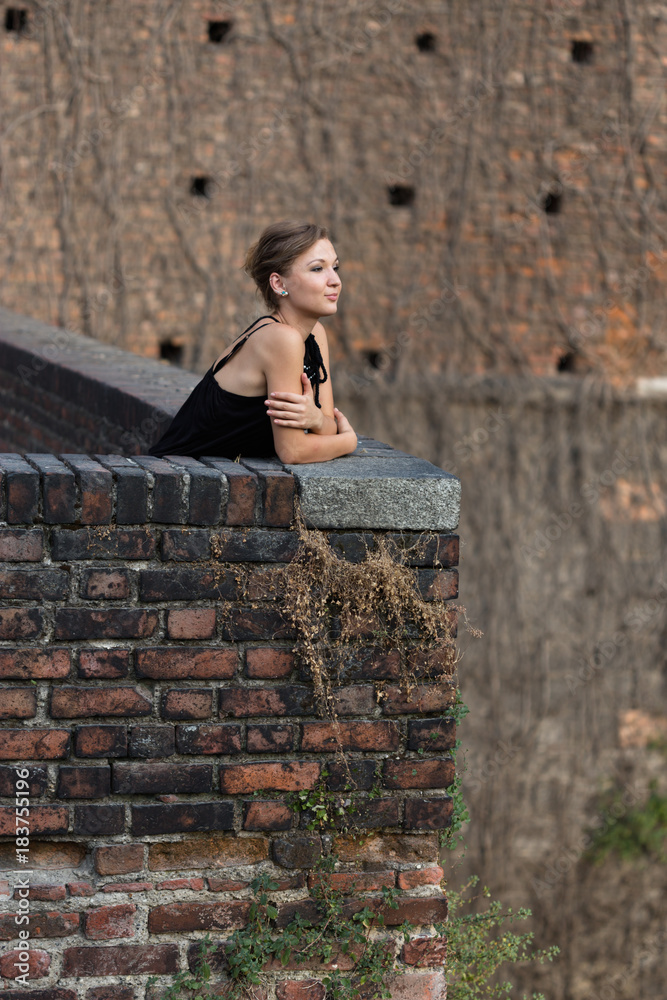 Beautiful girl dressed in black dress standing in castle