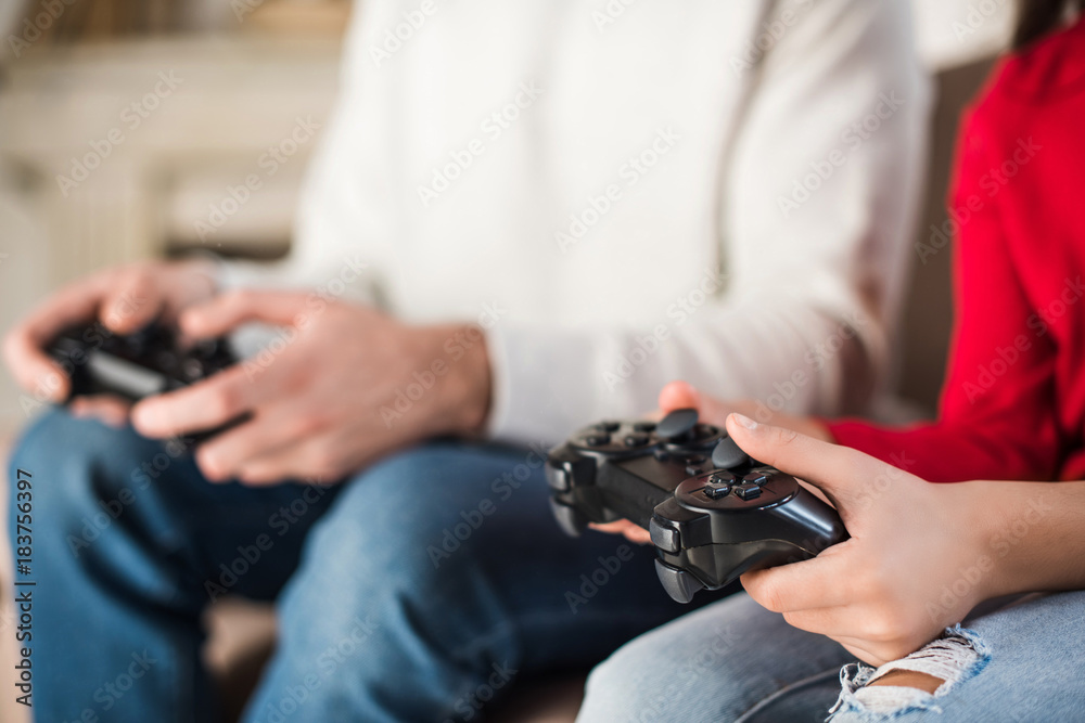 cropped image of father and daughter holding game pads cropped image of father and daughter holding game pads
