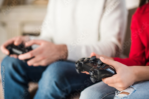 cropped image of father and daughter holding game pads