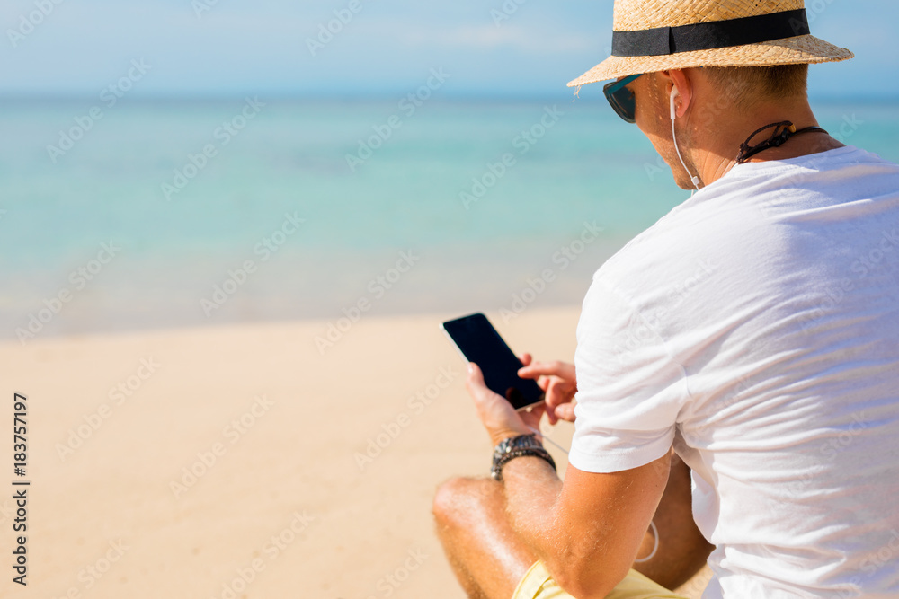 Guy using phone on the beach